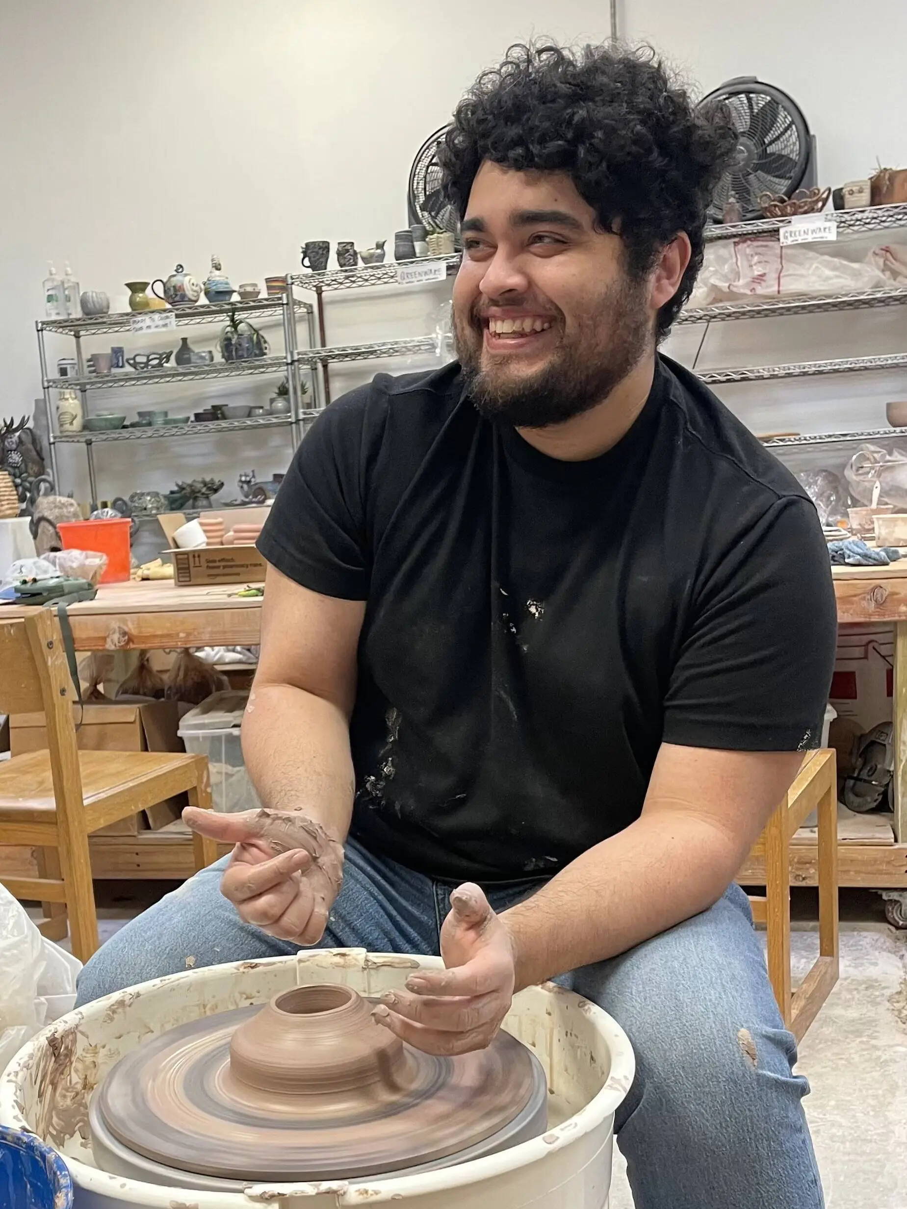 A student shaping clay on the pottery wheel